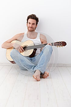 guitarist sitting on floor smiling