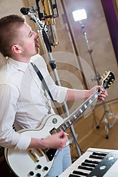 The guitarist stands next to the keyboard and sings