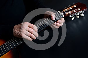 Guitarist tunes instrument, man plays the guitar, close-up hands, the concept of creativity, learning to play musical instruments