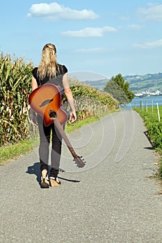 Guitarist walking down country road