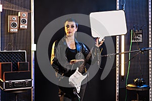 Guitarist woman showing blank placard with copy space for advertisement in music studio