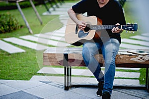 guitarist, a young man playing a guitar while sitting in a natural garden,music concept photo