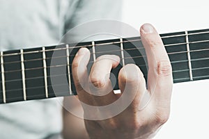 Guitarists hand playing an major barre chord on the fretboard of an classical guitar