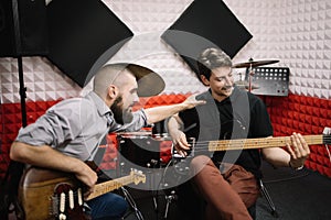 Guitarists sitting in soundproof studio and smiling