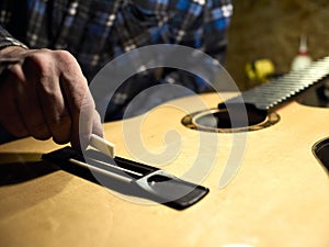 Guitars Luthiers installs a saddle.