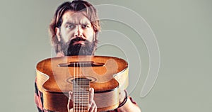 Guitars and strings. Bearded man playing guitar, holding an acoustic guitar in his hands