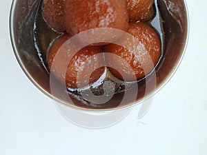 Gulab Jamoon or Jamun in a Steel, Green Color Plastic Cup and Spoon isolated on white Background