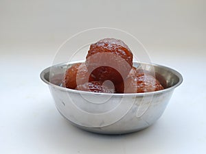 Gulab Jamoon or Jamun in a Steel, Green Color Plastic Cup and Spoon isolated on white Background