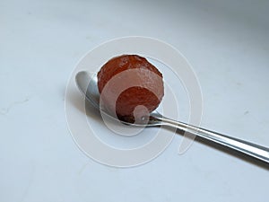 Gulab Jamoon or Jamun in a Steel, Green Color Plastic Cup and Spoon  on white Background