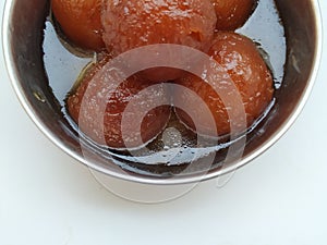 Gulab Jamoon or Jamun in a Steel, Green Color Plastic Cup and Spoon  on white Background