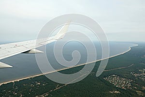 Gulf of Riga coastline with long sandy beaches on Baltic sea under flying airplane wing