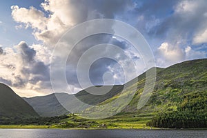 Gummeenduff lake and MacGillycuddys Reeks mountains illuminated by sunset light in Black Valley