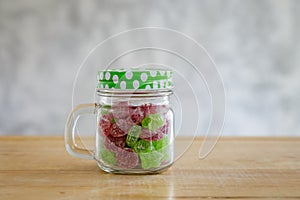 Gummy candies in a glass jar on wooden table.