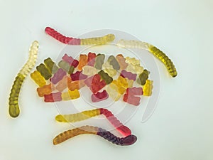 Gummy candies lie on a white matte background. gelatinous worms and bears of different colors intertwined with each other. mouth-