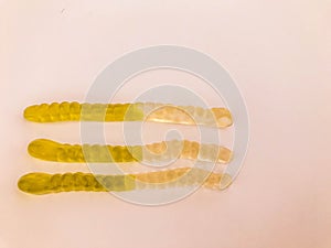 Gummy worms lie on a white matte background. bright, mouth-watering gelatinous worms of white-green colors. sweets with volumetric