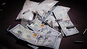 The gun and bullets fall down on the background of money and drugs. Criminal activity concept