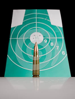 Gun cartridge over target with bulletholes