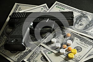 Gun and drug pills on dollar bills.