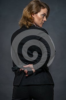 Gun in hand behind the back of a woman in a suit