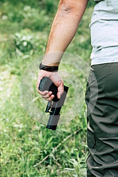 The gun is in his hand. The man is ready to shoot at the target.