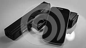 A gun and a modern smart phone, black and white