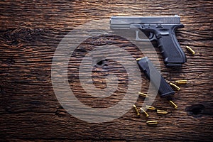Gun pistol. 9 mm pistol gun and bullets strewn on the rustic oak table