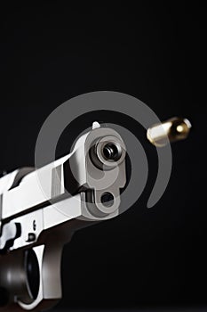 Gun shooting bullet on black background close up