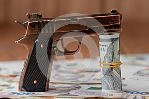 Gun and Stack of Money lying on the hryvnia on a wooden table. Drug use, crime, addiction and substance abuse concept on wooden