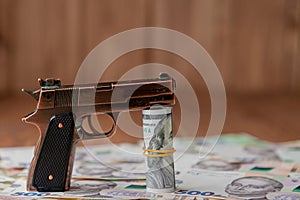 Gun and Stack of Money lying on the hryvnia on a wooden table. Drug use, crime, addiction and substance abuse concept on wooden