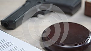 Gun on table, judge hitting gavel putting criminal in jail, accusation of murder