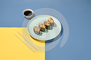 Gunkan sushi set in plate on coloured background with chopsticks and soy sauce. Minimal composition with japanesse food. Trendy photo