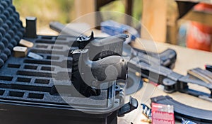 Guns stored in metal case on wooden table with clips and various ammunition. Military equipment, Firing range. Focus on