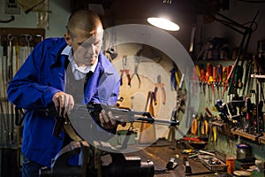 Gunsmith performing maintenance of Kalashnikov assault rifle in workshop