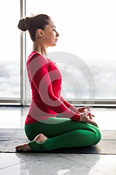 Guptasana. Beautiful yoga woman practice in a big window