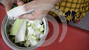 Gurgaon, India 2020: Cutting of Vegetable by a small knife into small pieces. Indian house wife chopping bottle gourd into small p