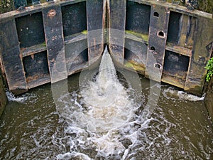 Gushing water leaking from wooden canal lock gates on the Leeds Liverpool Canal in Lancashire, England, UK
