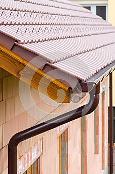 Gutter on house corner. Metal eave on roof