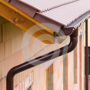 Gutter on house corner. Metal eave on roof