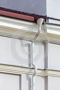 Gutter and white plaster wall