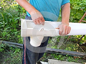 Guttering construction. Contractor installing rain gutter downspout drain pipe