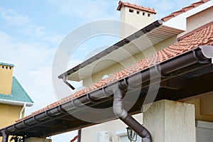 Guttering. Roof gutter pipeline sysem. House rain gutter with holders and downspout pipe