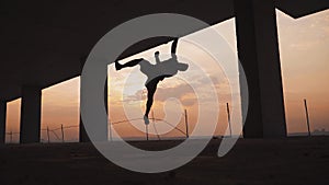 The guy is an acrobat doing flips in the background of a beautiful sunset in an abandoned building. Parkour. Slow motion