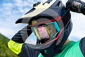 Guy adjusting motorcycle motocross helmet with goggles, close-up shot of relaxing while riding bike or dirt bike