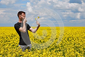 a guy with an allergy to pollen in a rapeseed field closes his nose
