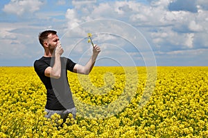 a guy with an allergy to pollen in a rapeseed field closes his nose