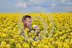 a guy with an allergy to pollen in a rapeseed field closes his nose