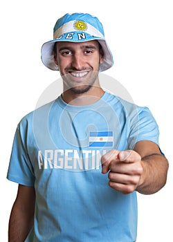 Guy with argentinian jersey and hat pointing at camera