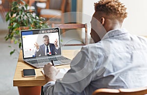 Guy attending online training with business coach, listening, taking notes