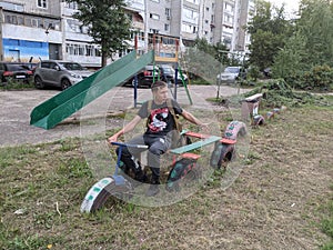 A guy with a backpack sits on a toy bike