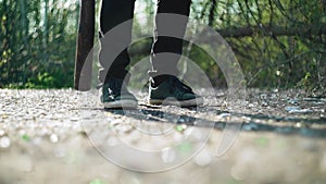 A guy with a baseball bat walks past the camera. Shooting legs. Close up